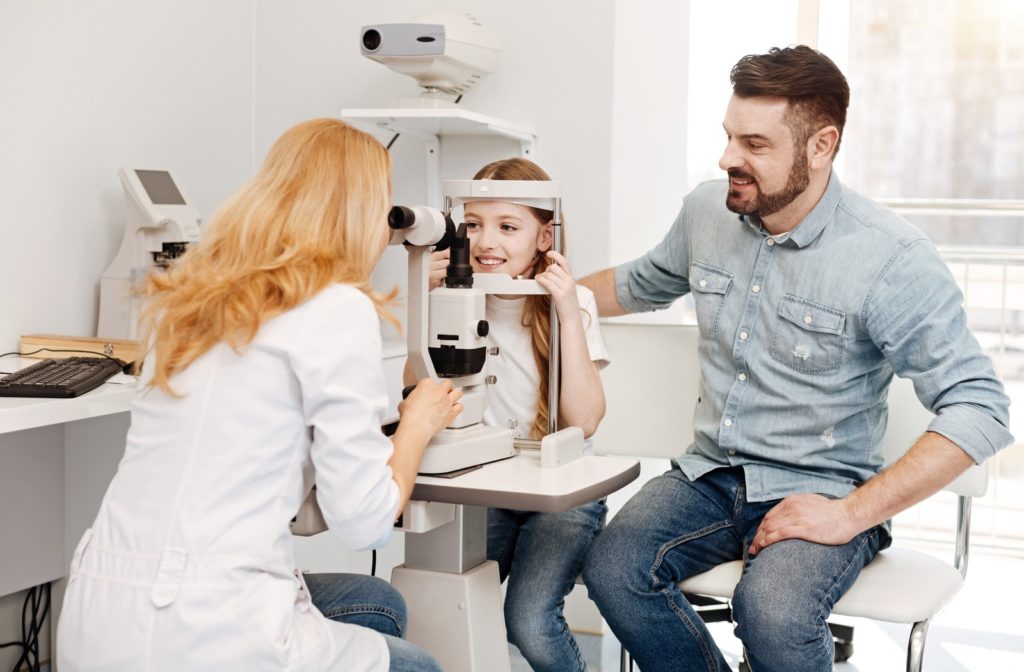 Optometrist checks out child's eye as her father accompanies her through out the exam.