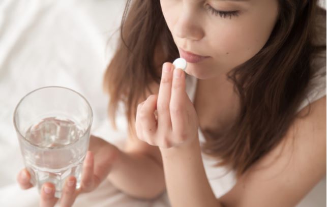 Women taking pill which she should inform her optometrist about during eye exam