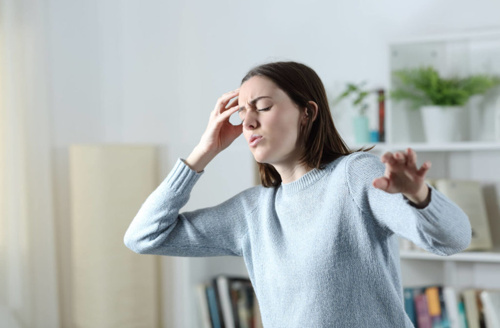 A woman with an eye condition gets dizzy while standing in the living room at home.