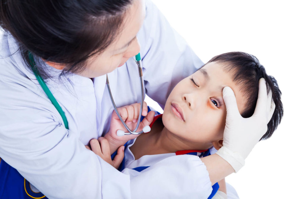 A female eye doctor is removing a foreign object from the eye of a boy.