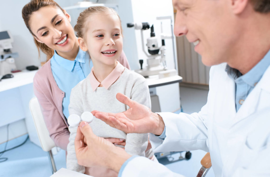 A male eye doctor is giving the prescribed contact lenses to his young female child patient.