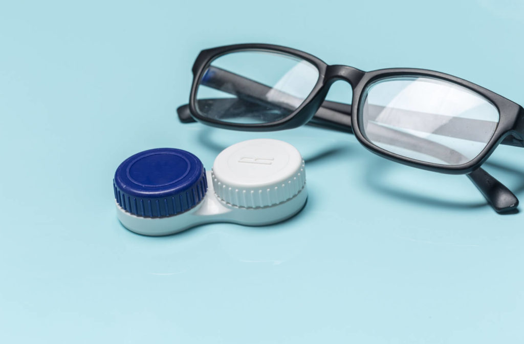 A pair of eyeglasses and a contact lens case sitting on a blue surface