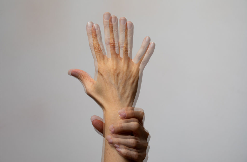 A double image of a hand with another hand holding onto the wrist to keep it steady.