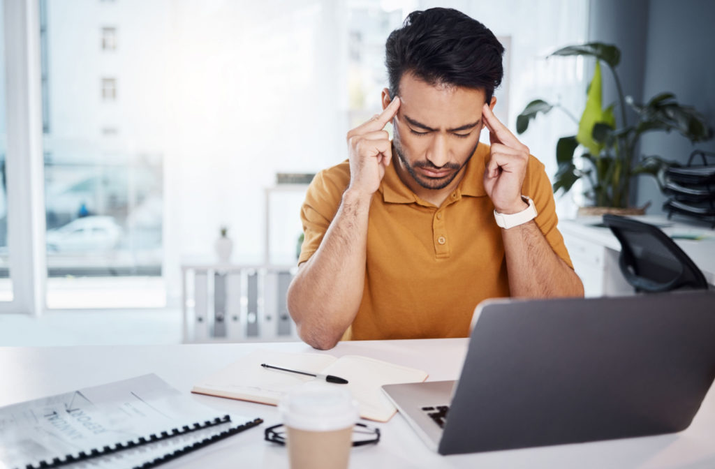 A professional suffering a headache while using his laptop.