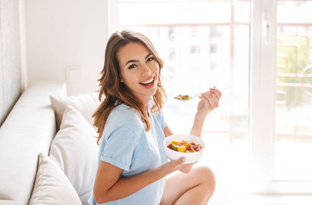 A woman enjoying a bowl of salad in a brightly lit room.