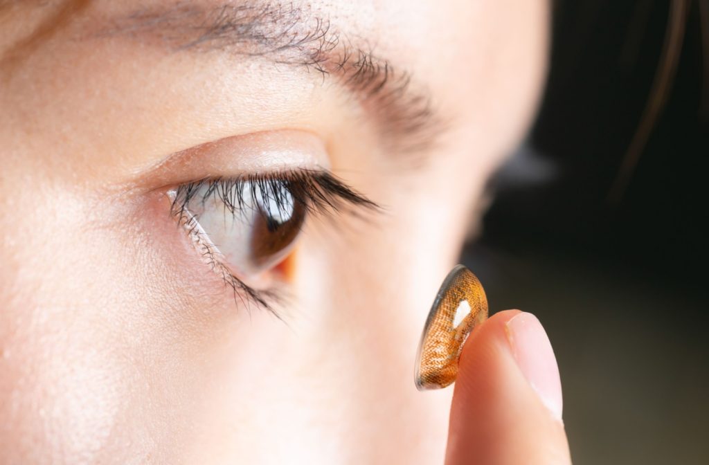 A close-up of a patient inserting a brown-colored contact lens.