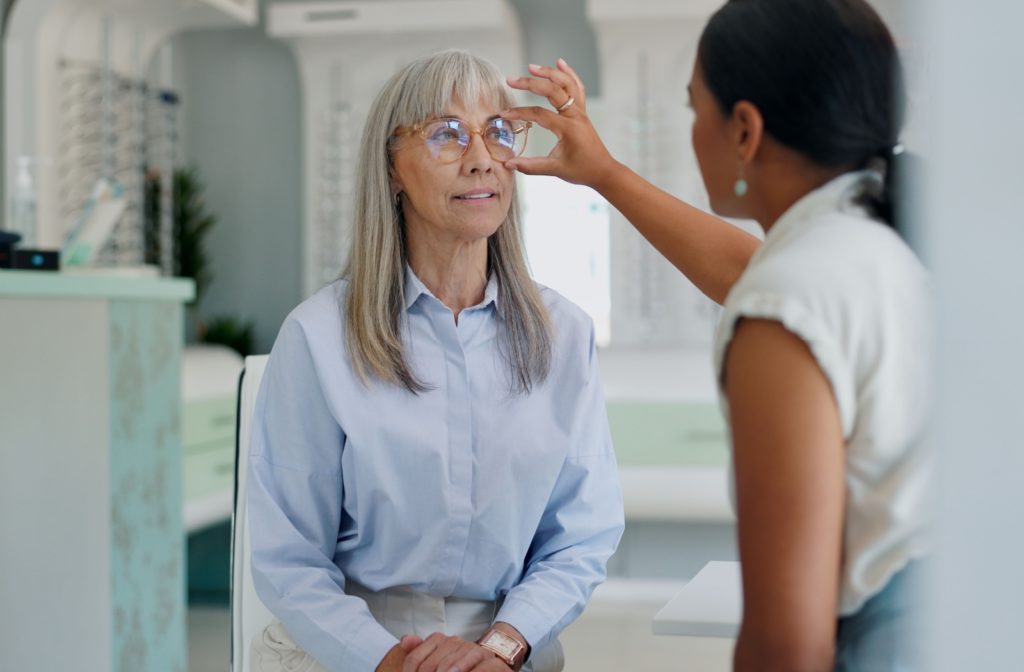 Optician helping senior find the right pair of glasses, in an optometry office.