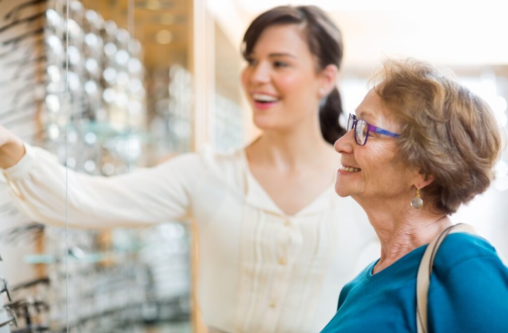 Person browsing eyeglass frames with help from an optical staff member in a vision care clinic