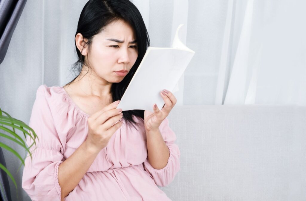 An adult holds a book close to their face and squints to read it.