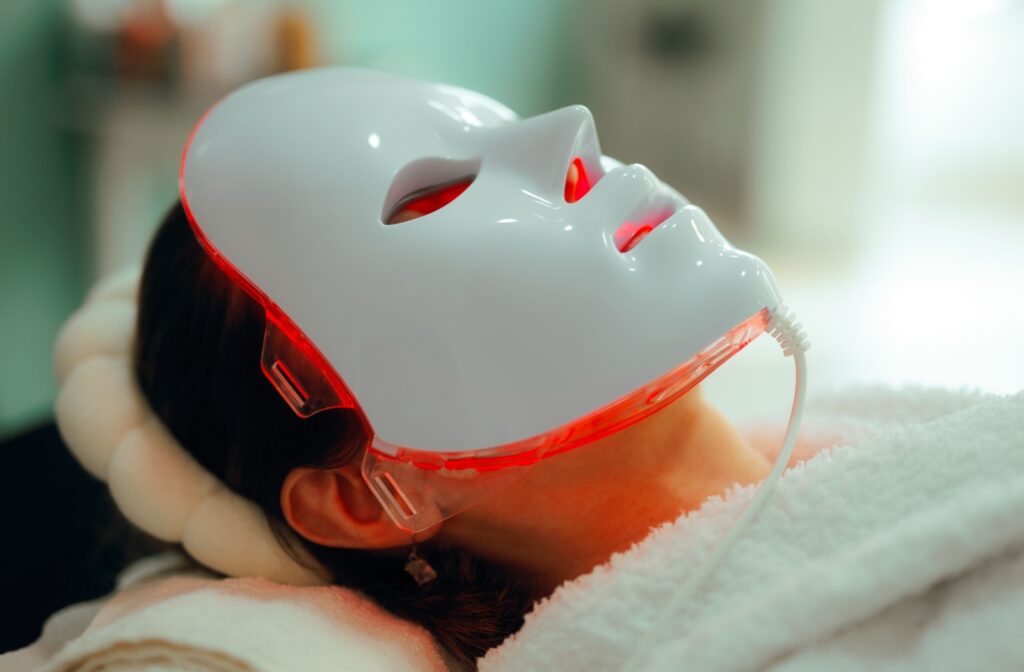 A person laying down, wearing a red light mask